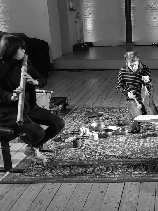 Violeta Motta with her homemade flute and Rodolphe Loubatière with his percussion: black-and-white photo of Forbidden Color musicians performing