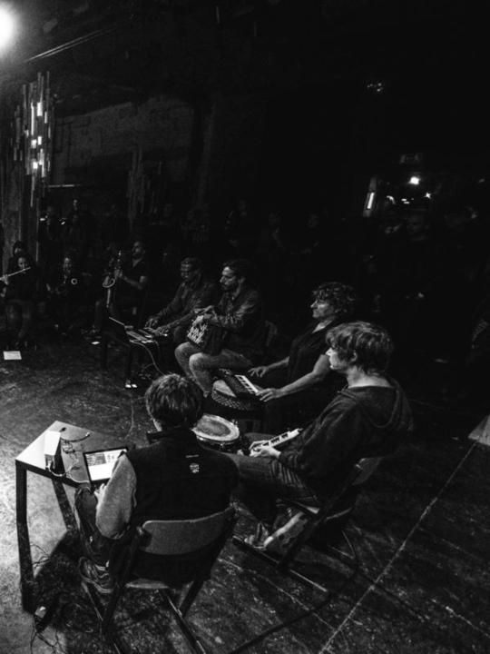 The Insub. Meta Orchestra performing: live ensemble footage with multiple musicians, black and white