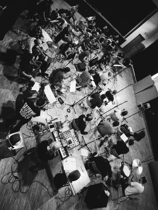 The Insub. Meta Orchestra performing: live ensemble footage with multiple musicians, black and white